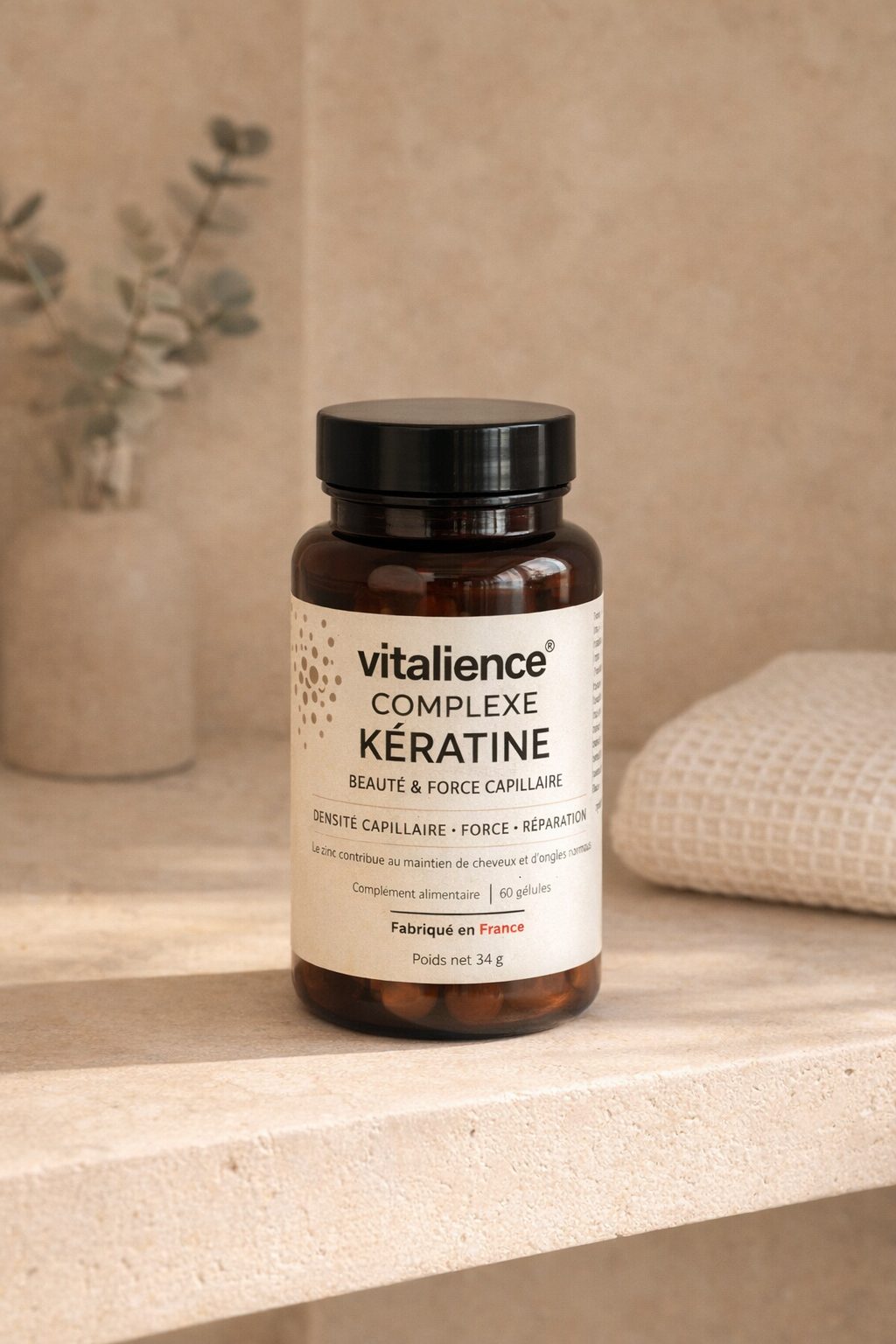 Flacon Complexe Kératine Vitalience posé sur une tablette en travertin, serviette en coton et eucalyptus en arrière-plan, lumière douce du matin.